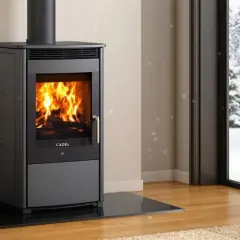 Poêle à bois Cadel en feu, avec une vue sur un paysage enneigé. L'alarme pressostat assure un fonctionnement sûr.
