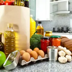Un sacco di carta pieno di pomodori, uova, pane, formaggio e altri cibi proteici, pronti per essere cucinati.