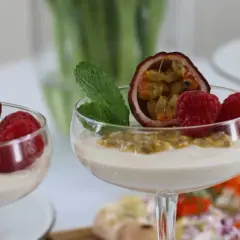 Två glas med len vit chokladmousse, toppade med passionsfrukt, hallon och mynta. En läcker dessert som passar perfekt till fikat.