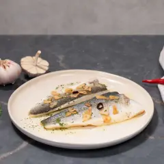 Dos filetes de lubina a la donostiarra, con láminas de ajo dorado, perejil picado y un toque de guindilla.