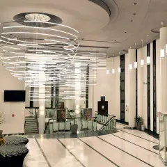 Nowoczesny, przestronny foyer z imponującą, wielopoziomową lampą i szklaną gablotą z rzeźbą.