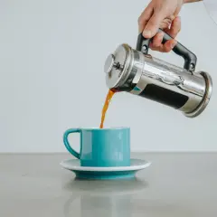 Ręka przelewa aromatyczną kawę bez fusów z zaparzacza do turkusowej filiżanki. Idealny poranek.