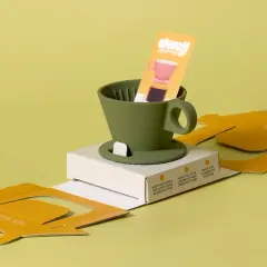 Minimalist packaging design trends 2024: a green coffee dripper with instructions on a yellow cardboard box.