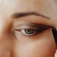 Application d'un fard brun pour comment maquiller des yeux verts. Un pinceau est utilisé pour définir la paupière.