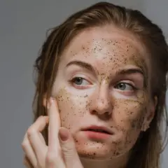 Una donna applica uno scrub viso, scoprendo i benefici di una pelle liscia e luminosa.