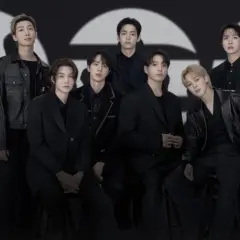 Die Mitglieder von BTS posieren in schicken schwarzen Outfits vor einem großen, stilisierten "GQ"-Logo.