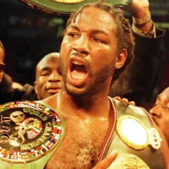 Lennox Lewis, triumphant, wears multiple championship belts, a symbol of his boxing dominance.
