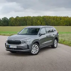 Szary Skoda Kodiaq hybryda na tle jesiennego krajobrazu.
