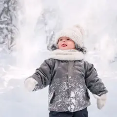 Dziecko w zimowej kurtce i czapce rzuca śnieżkami, jakby czytało wiersz o zimie Tuwima.
