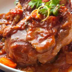 Herzhaftes Ossobuco Rezept in Tomatensoße mit Karotten und Petersilie, serviert in einer weißen Schüssel.