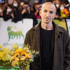 Un uomo con un mazzo di fiori, forse pensando ai testi di Fabrizio De André nella sua ora di libertà.