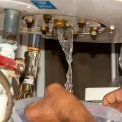 Fuite d'eau au niveau du ballon d'eau chaude, un plombier intervient pour l'entretien.