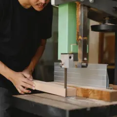 Un artisan utilise une scie stationnaire pour découper une pièce de bois.