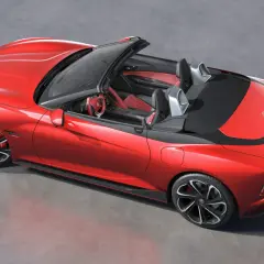 Czerwony MG Roadster z otwartym dachem, sportowe fotele i kierownica.