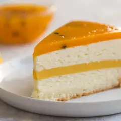 Pyszny kawałek tortu z warstwami białego kremu i żółtym musem mango, zwieńczony galaretką z mango.