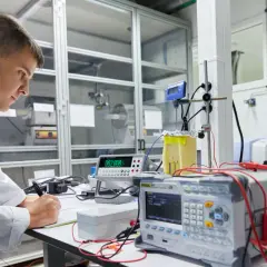 Científico en laboratorio registrando datos de un experimento de transferencia de calor con equipos electrónicos.