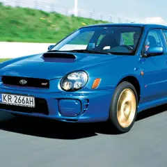 Niebieskie, małe szybkie auto Subaru Impreza WRX STI pędzi po torze wyścigowym.