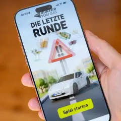 App "Die letzte Runde" warnt vor Fahren mit 0.3 Promille. Ein Auto, Gläser und ein Warnschild sind zu sehen.