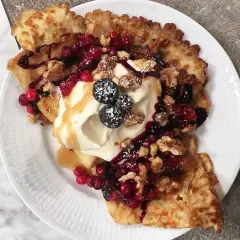 En härlig funnel cake toppad med vispgrädde, bär, nötter och sirap. En dröm för alla sötsugna!