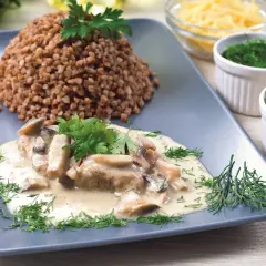 Schab duszony z pieczarkami w kremowym sosie, podany z kaszą gryczaną i świeżymi ziołami. Pyszne danie obiadowe.