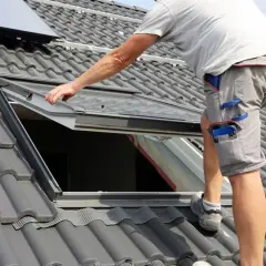 Hand führt ein Dachfenster ein, um es auf dem Ziegeldach zu montieren.
