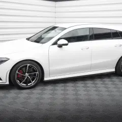 Biały Mercedes CLA shooting brake z czarnymi felgami i czerwonymi zaciskami hamulcowymi stoi na szarej, kratkowanej podłodze.