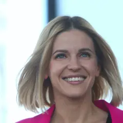 Uśmiechnięta Aleksandra Gajewska, której wykształcenie jest szeroko komentowane, w różowym żakiecie.