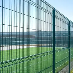 Zielona siatka ogrodzeniowa otacza boisko. Czy można ogrodzić działkę rolną podobnym płotem?