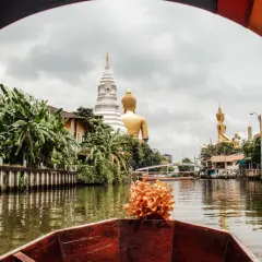 Bootsfahrt auf einem Kanal in Bangkok mit Blick auf goldene Buddha-Statuen und Tempel. Entdecken Sie diese Bangkok Geheimtipps abseits der ausgetretenen Pfade.