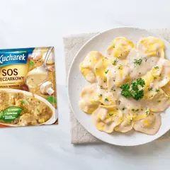 Ravioli polane kremowym sosem pieczarkowym, obok opakowanie sosu Kucharek.