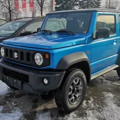 Niebieski Suzuki Jimny 2026 gotowy na zimowe przygody, zaparkowany na śniegu obok innych samochodów.