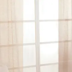 Tende leggere color crema coprono una finestra con divisori bianchi. L'altezza del bastone tende dal soffitto è ottimale per un look arioso.