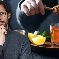 Hombre pensativo mira cómo añaden miel a un vaso de agua con limón y menta, ¿será la bebida perfecta para la noche?