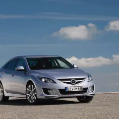 Srebrna Mazda 6 2.0 benzyna na tle błękitnego nieba z chmurami.
