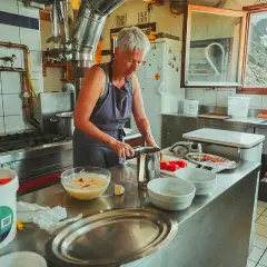 Une femme prépare des ingrédients dans une cuisine de montagne, un aperçu de son quotidien à travailler dans un refuge.