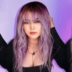 Una joven con cabello ondulado en una gama de violetas, con flequillo y collares delicados.