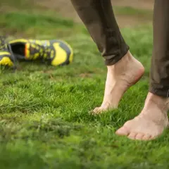 Stopy na trawie, buty biegowe leżą obok. Czas na bieganie boso i poczucie wolności.