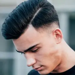 Ein Mann mit einem modernen Undercut für Herren, die Haare zur Seite gescheitelt und am Hinterkopf kurz rasiert.