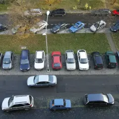 Wiele samochodów zaparkowanych pod blokiem, przypominające o przepisach parkowania.