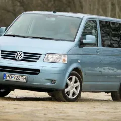 Jasnoniebieski Volkswagen Transporter T5 na drodze gruntowej.