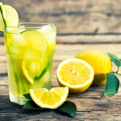 Vaso de limonada refrescante con rodajas de lima y limón, mostrando la diferencia entre lima y limón.