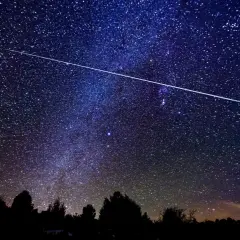 Una estrella fugaz cruza el cielo nocturno estrellado, ideal para ver las Perseidas en Madrid.