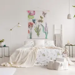 Sypialnia w stylu shabby chic z pościelą w kwiaty, narzutą i obrazem z ptakami i kwiatami.