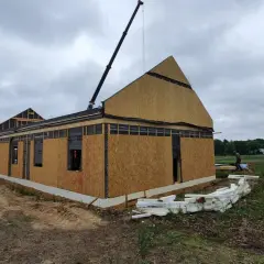 Budowa domu z prefabrykatów w toku. Dźwig montuje elementy dachu. Zastanawiasz się, ile kosztuje dom z prefabrykatów?