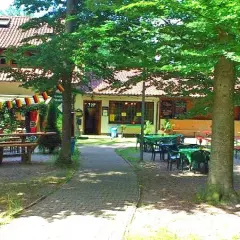 Idyllischer Biergarten mit vielen Tischen und Bänken unter Bäumen, dekoriert mit Deutschlandflaggen. Einladend für ein Treffen im Waldheim Backnang.