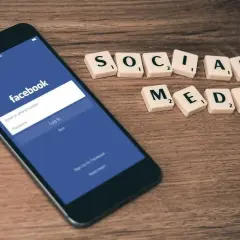 Smartfon z ekranem logowania Facebooka i kafelki z napisem "SOCIAL MEDIA".