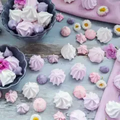 Zarte Baisers in Rosa, Lila und Weiß, perfekt für ein süßes Baiser Rezept. Kleine Blumen schmücken die Leckereien.