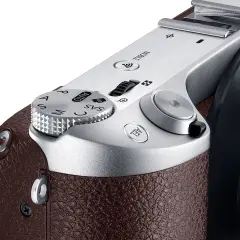 Zbliżenie na górną część eleganckiej, brązowej obudowy aparatu samsung lustrzanka cyfrowa. Widoczny pokrętło trybów i przyciski.