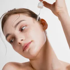 Delikatna skóra kobiety otrzymuje kroplę serum. Zobacz, co daje serum do twarzy dla promiennej cery.