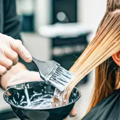 Hårstylist applicerar färg för att skapa slingor i grått hår.